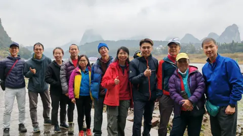 攀岩同好在陽朔河畔合照，身後是山峰景色